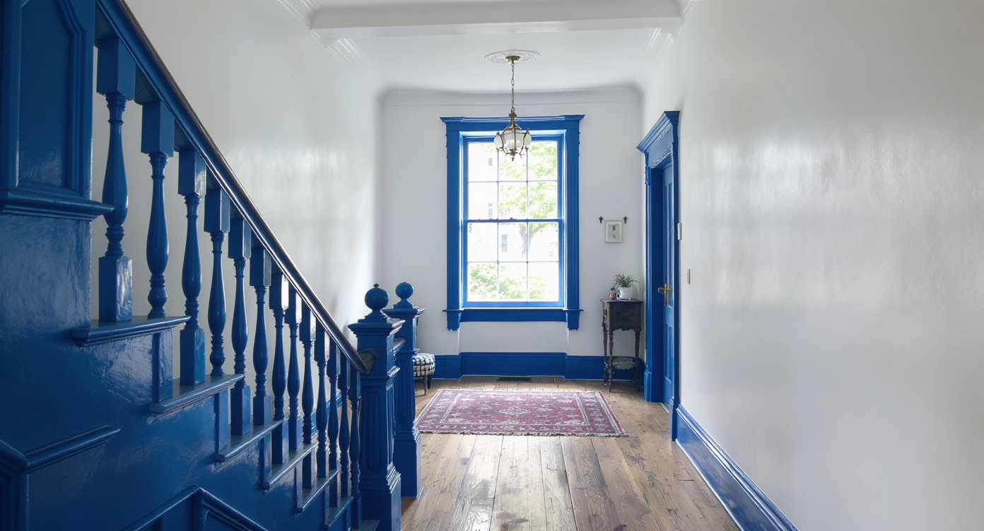 A Victorian hallway with white walls and ceiling, accented by bold blue stair balusters and trim, realistic lighting, and hardwood floors.