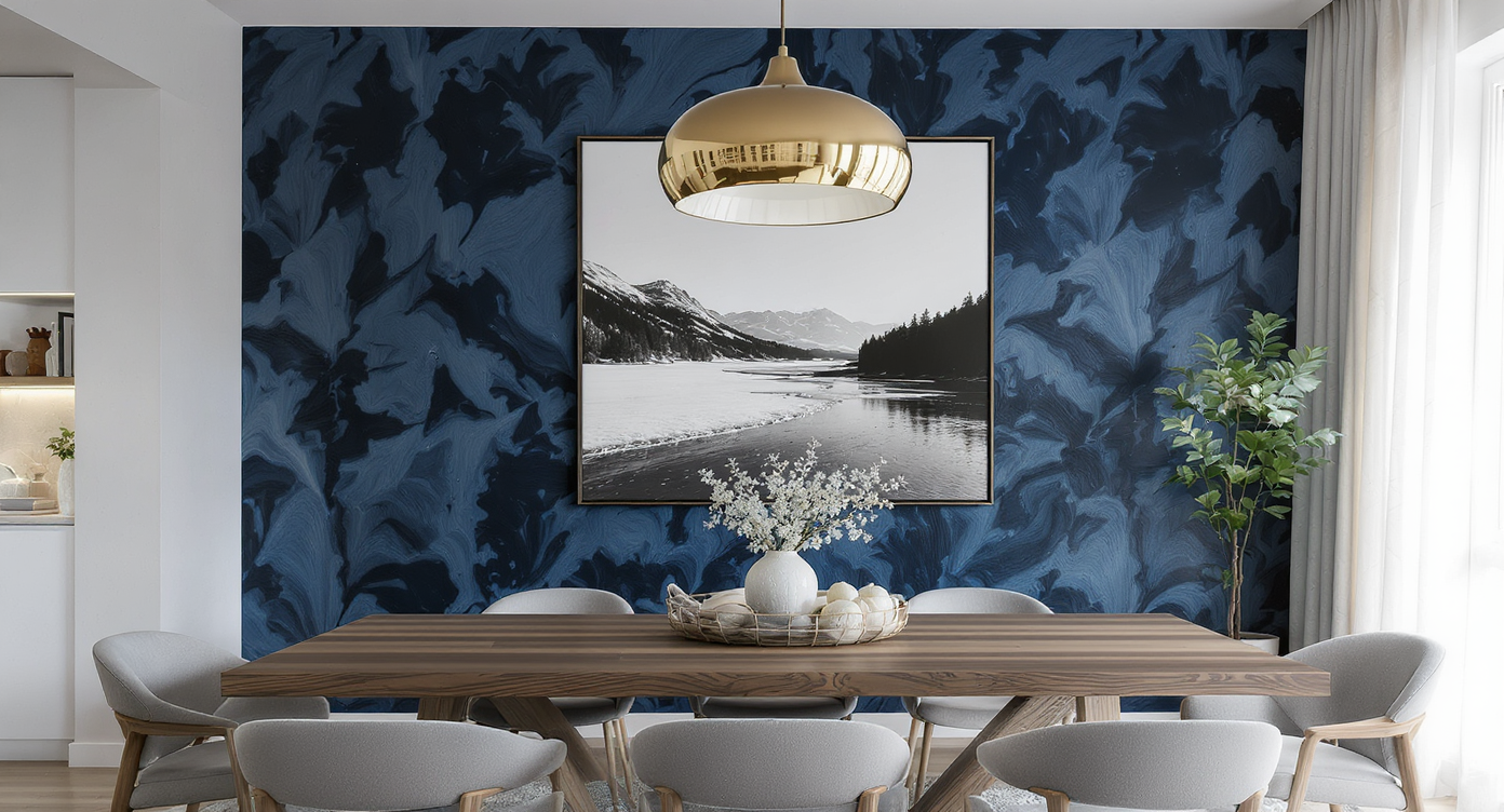 A chic dining room featuring a textured ink-blue accent wall, brass lighting, a large art photograph, candles, and paint samples on a sideboard.