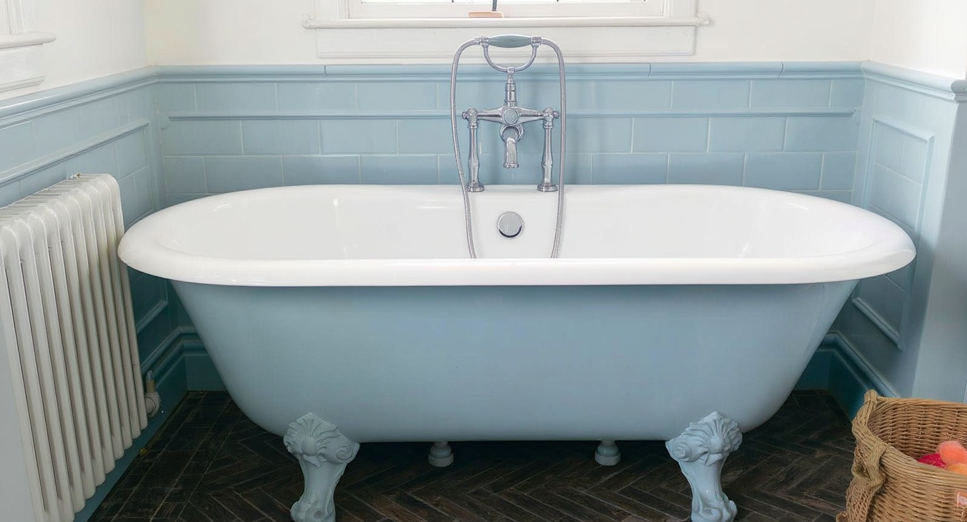 A vintage-inspired bathroom with a baby blue bathtub, matching blue vanity, and coordinated retro wallpaper, textiles, and accessories.
