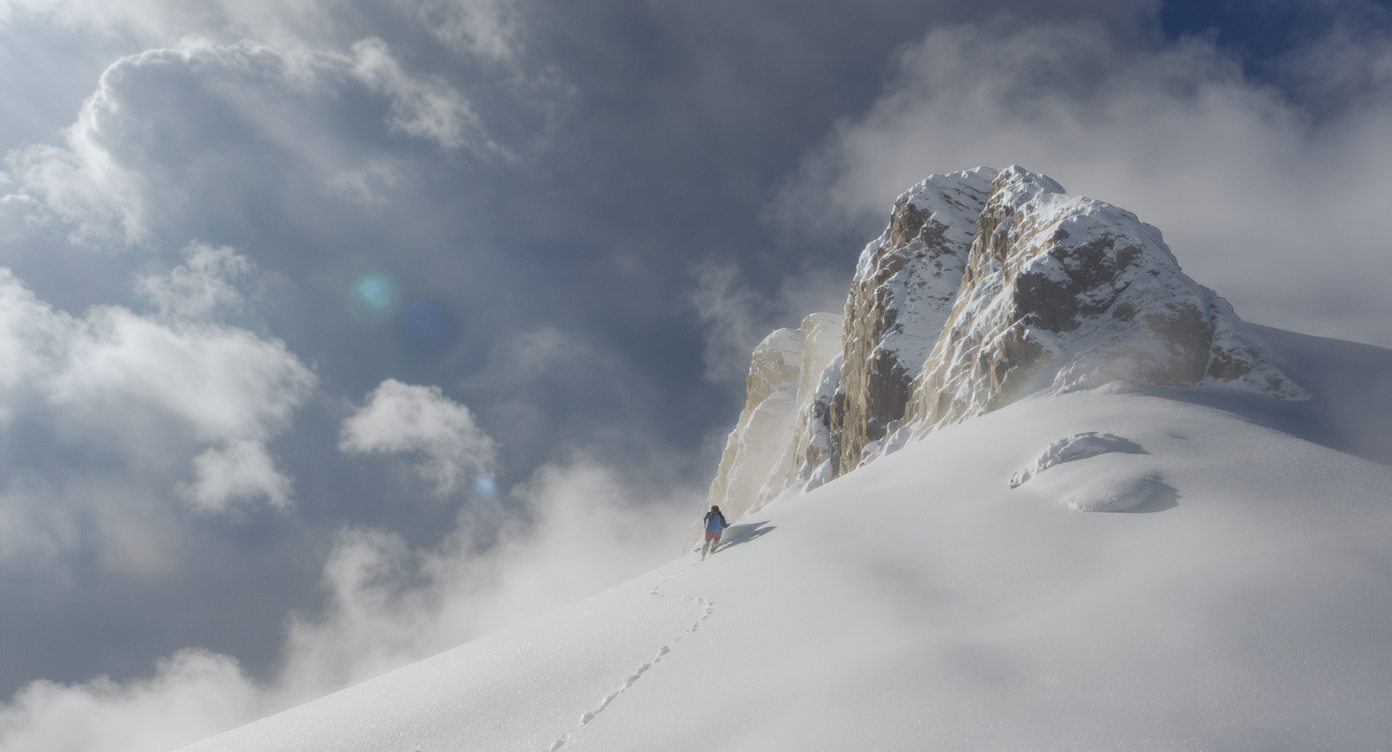 A sunlit, narrow bedroom corridor with pale wood floors, minimal built-in storage on one side, and a window at the end, showing underused space.