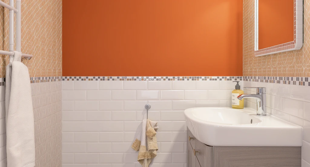 Modern bathroom with peel and stick tiles stopping at mid-wall under the vanity, bold reddish orange paint above, and wallpaper accents, showing rental-friendly bathroom color ideas and best colors for small bathrooms 2025.