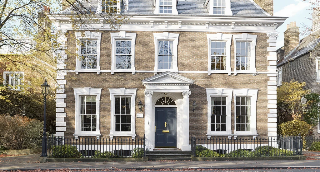 Updated historic home facade with proportionally enlarged sash windows, robust window casings, and transoms, showing how to enhance exterior curb appeal, restore historical home exterior features, and add architectural trim for the best ways to update the front entryway.