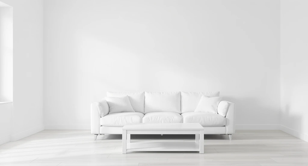 Minimalist living room with all-white walls, a white sofa, and white furniture under cool lighting, showcasing a sterile white interior design setting.