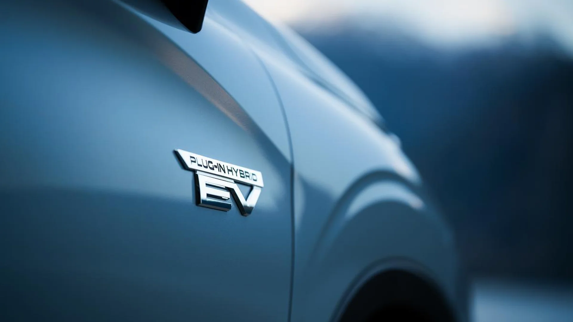 Close-up of a silver car badge that reads Plug-In Hybrid EV on a blue car door.
