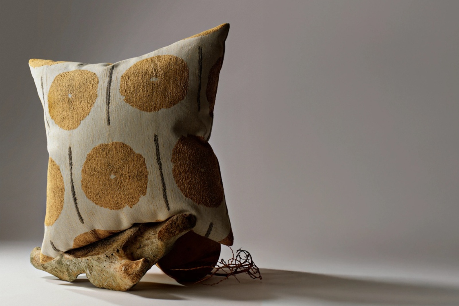Horizontal campaign photograph of a yellow-patterned Elaine Smith pillow with sculptural props