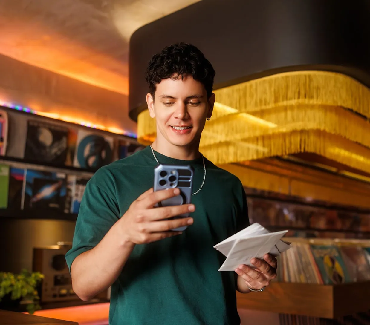 Un joven sostiene un teléfono celular y un papel.