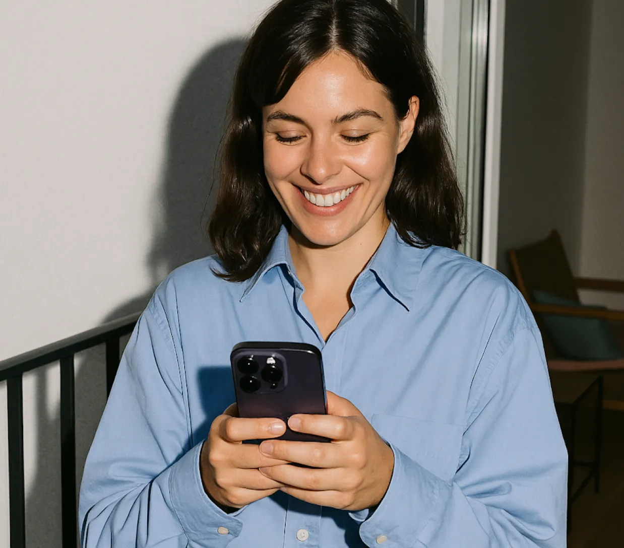 Una mujer sonríe mientras mira su teléfono móvil.