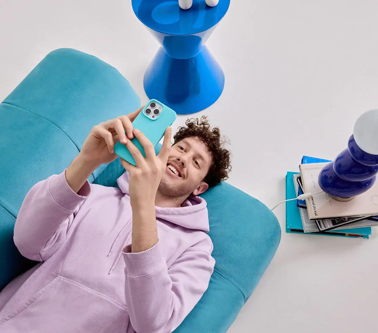 Un hombre sentado en un sofá azul con un teléfono celular.