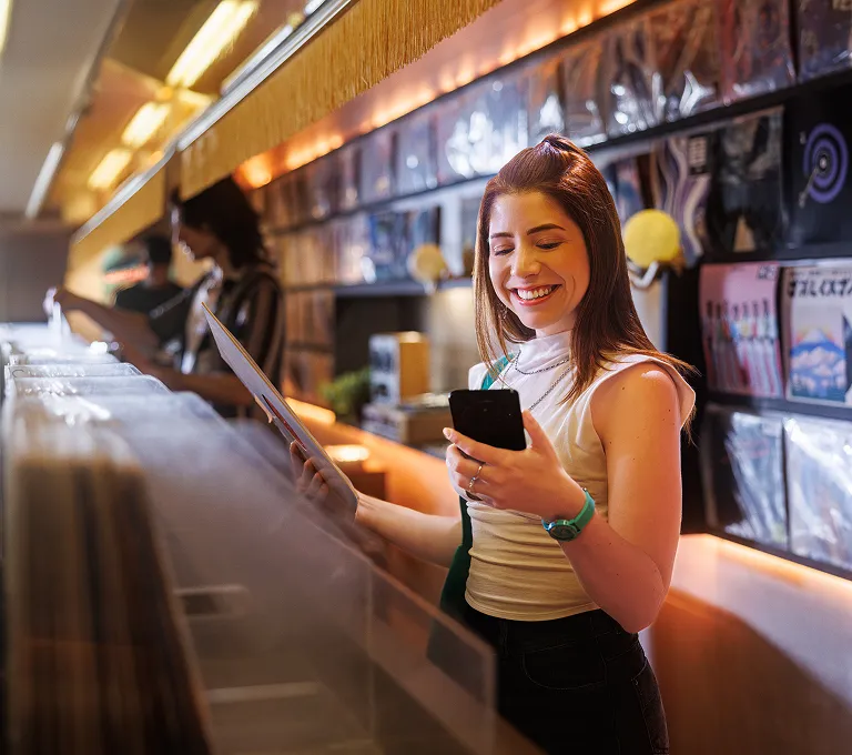 Uma mulher em frente a um balcão segurando um telefone celular.