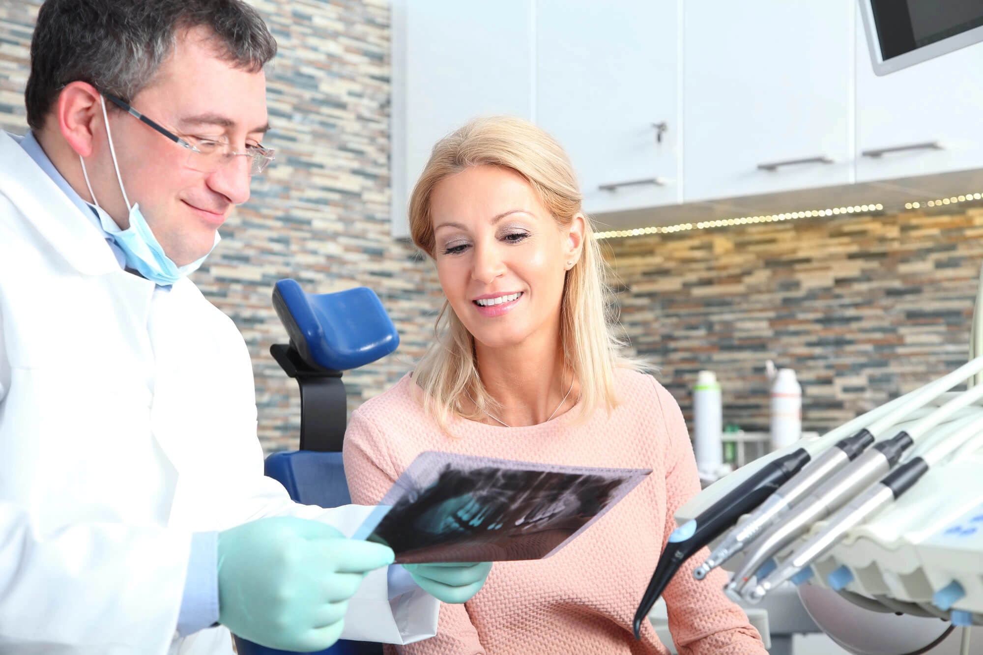 Dentist in gloves reviewing dental X-ray with female patient in a modern dental office