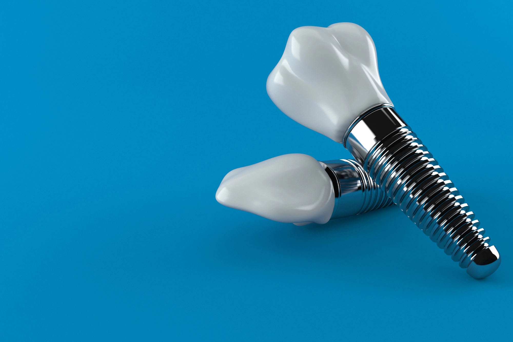 Two dental implants with white tooth crowns and metallic screw bases on a blue background