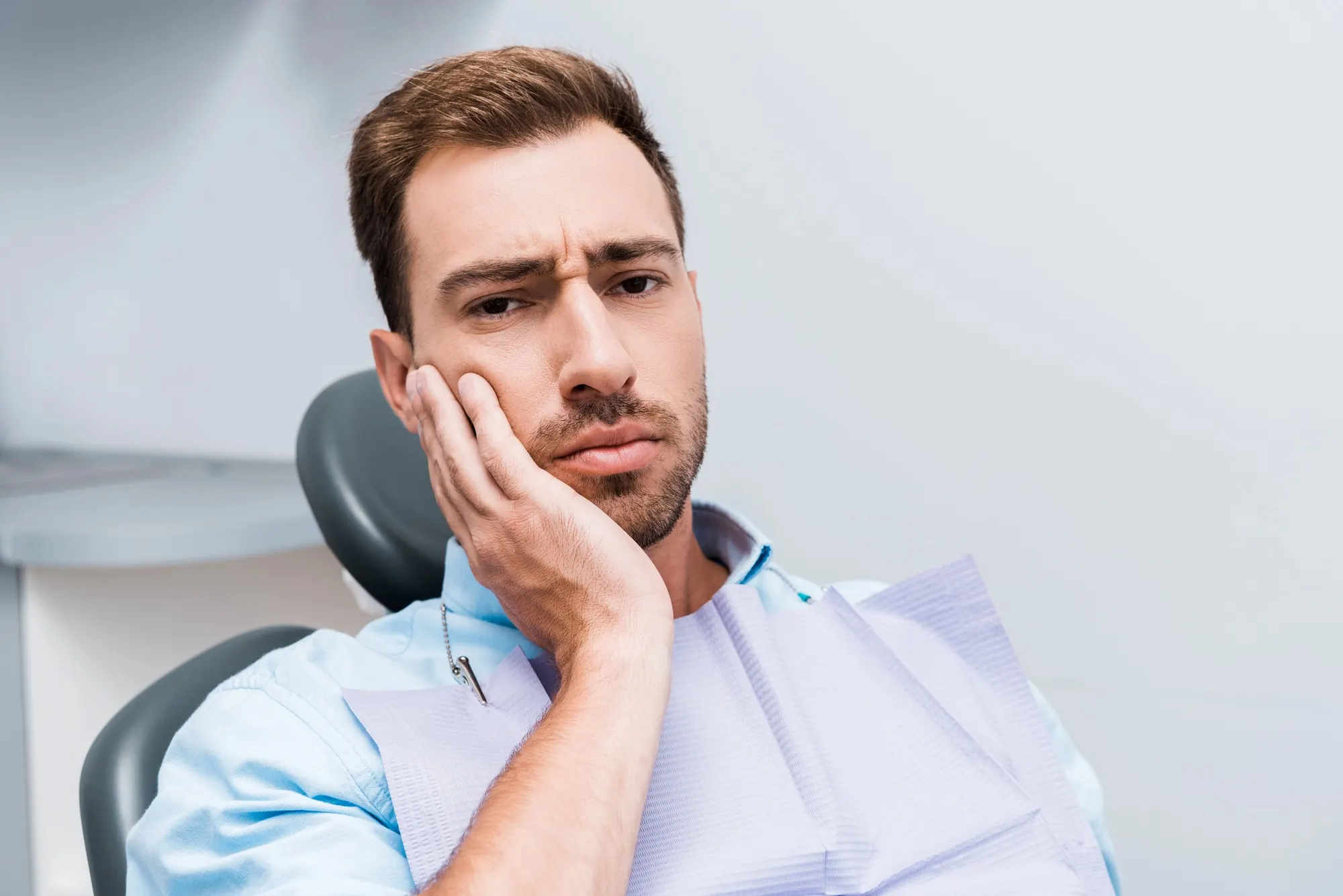 Man sitting in a dental chair with tooth pain before emergency dentist Frankfort KY treatment