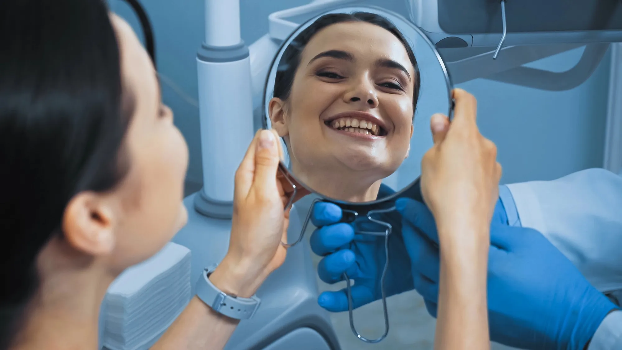 Patient checking her smile in a handheld mirror during a denture appointment in Lexington KY