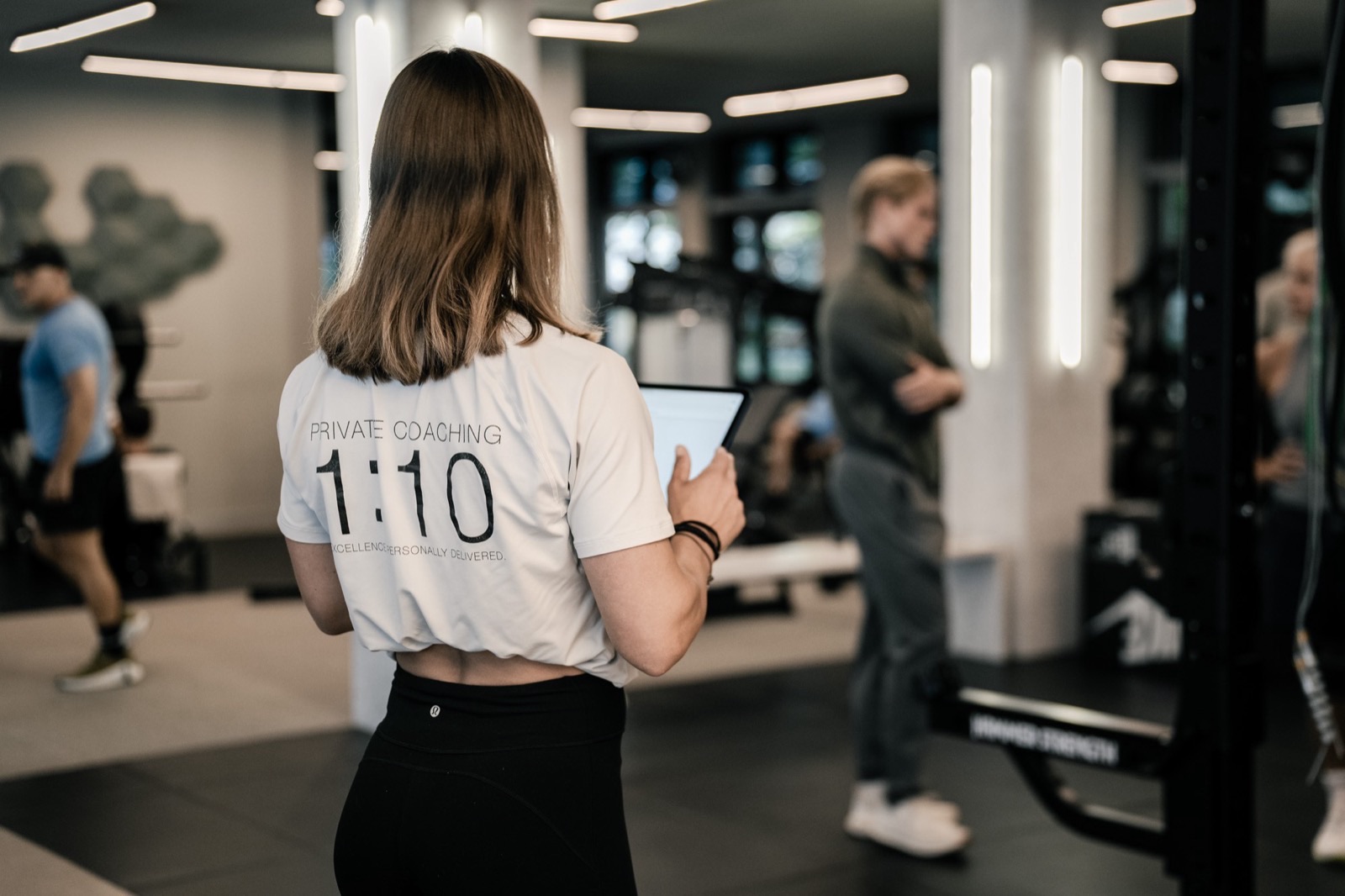 Trainerin mit Tablet auf der Trainingsfl&auml;che, Shirt mit Aufdruck Private Coaching 1:10