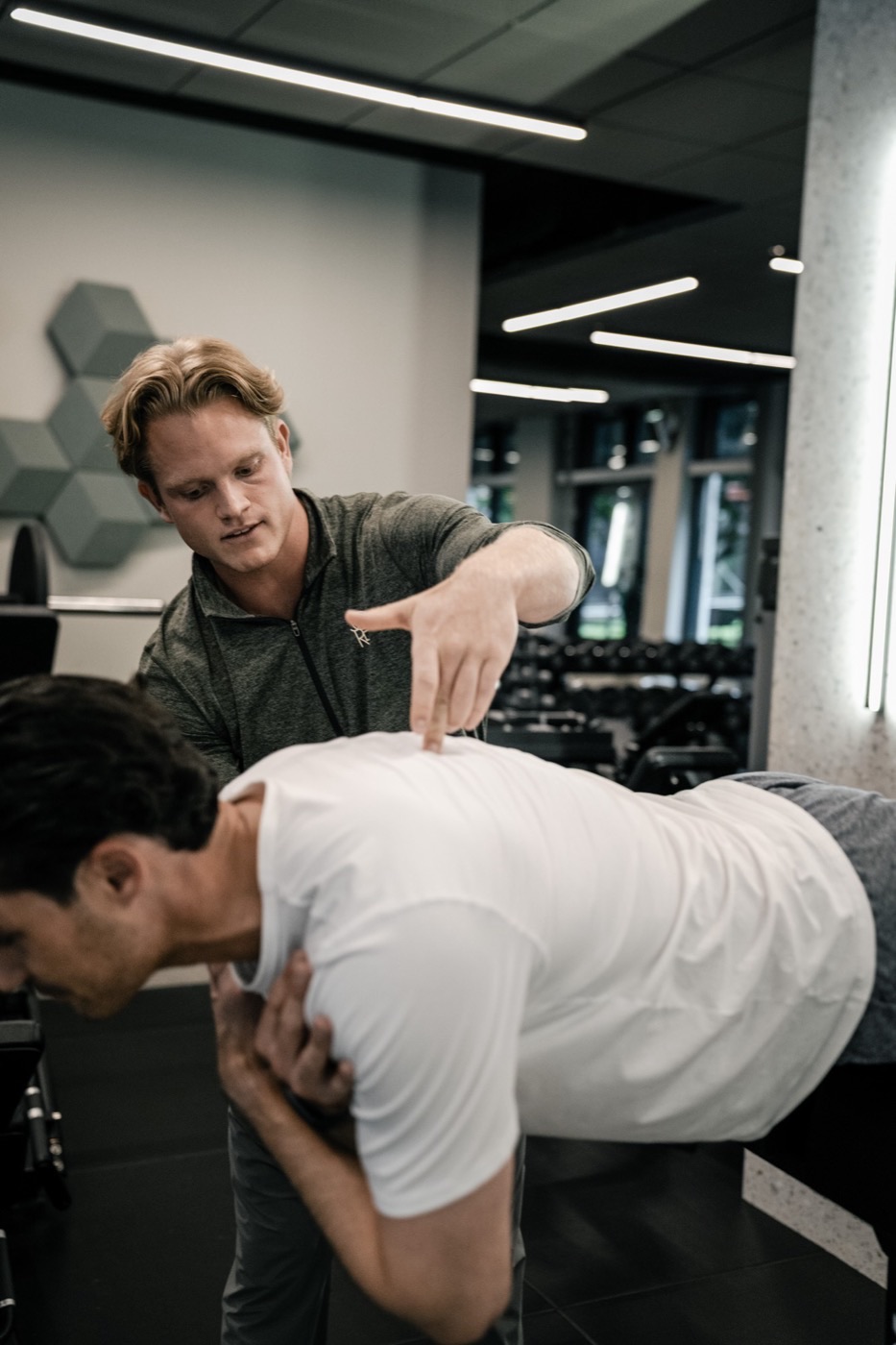 Trainer korrigiert die Haltung eines Mitglieds im Eins-zu-eins Training