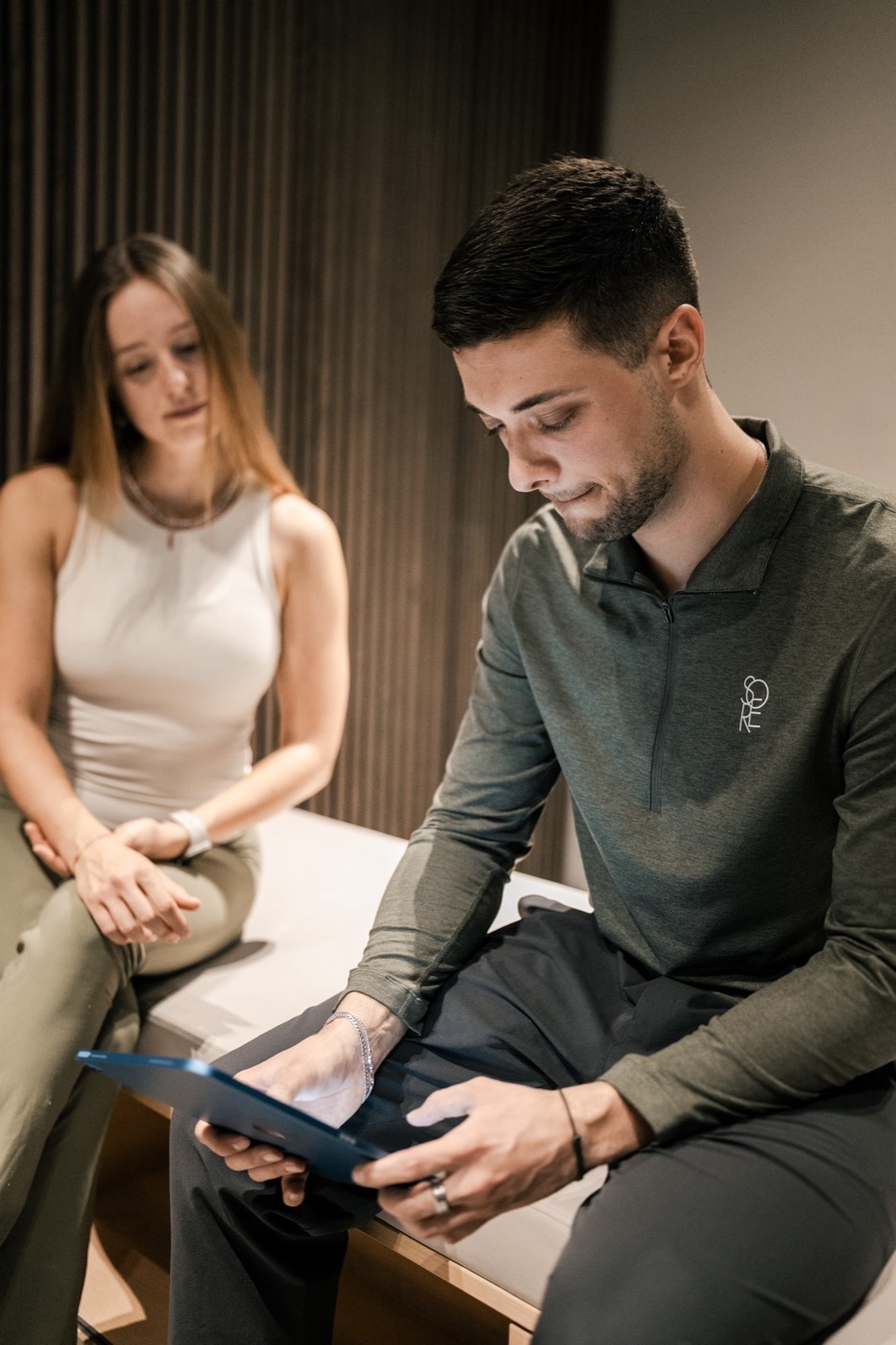Trainer geht mit einem Mitglied den Trainingsplan auf dem Tablet durch