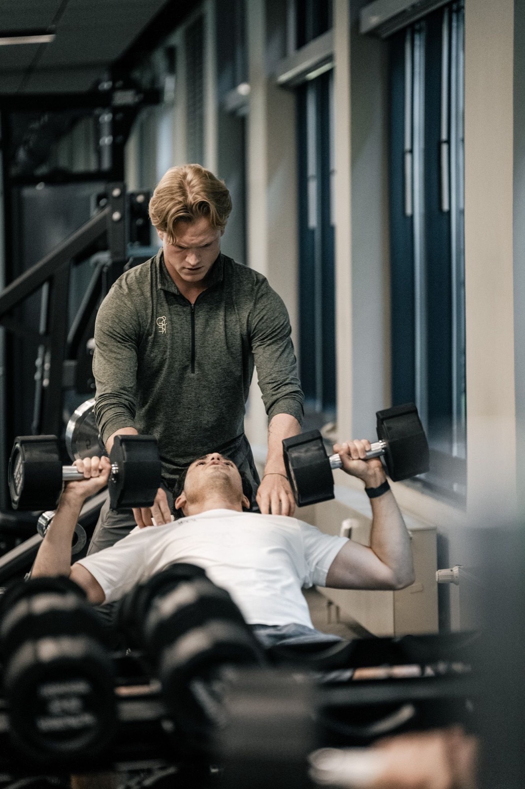 Trainer begleitet ein Mitglied beim Kurzhantel-Bankdr&uuml;cken im SŌRE Health Club