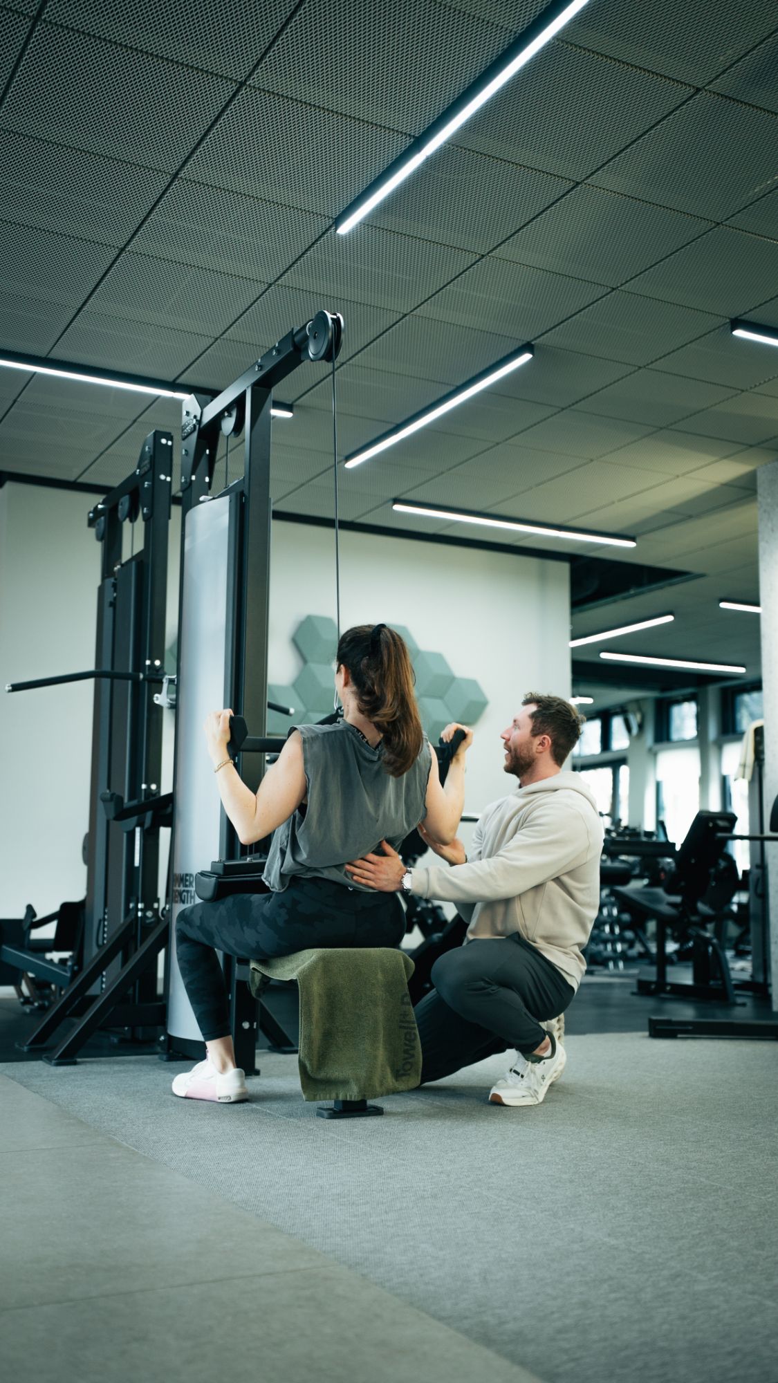 Trainerin betreut ein Mitglied beim Schlingentraining im SŌRE Health Club