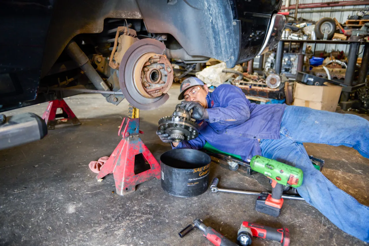 Wheel hub replacement underway as a heavy-duty technician installs a hub assembly under a lifted truck, with SAE gear oil nearby.