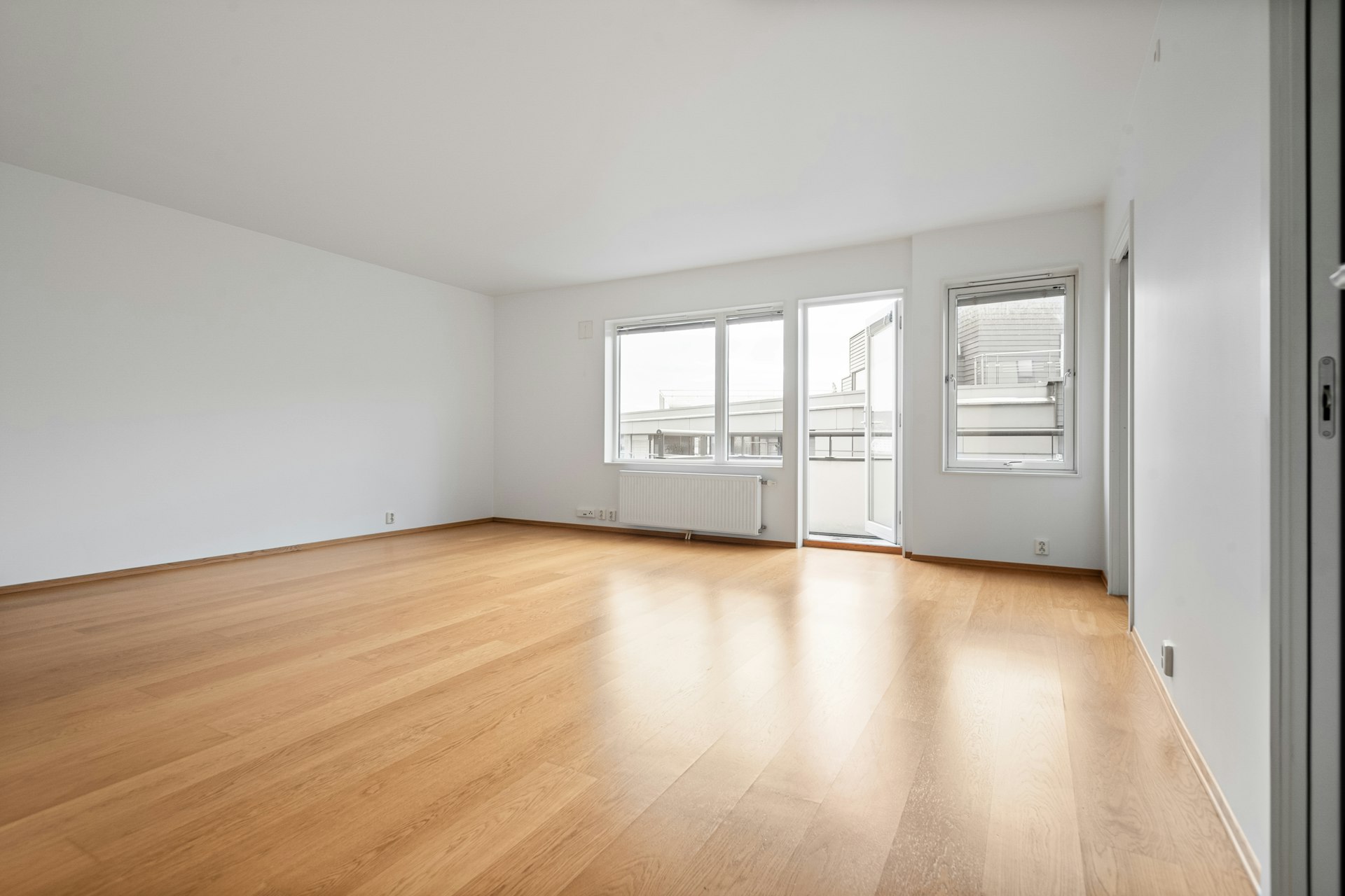 An empty apartment room with wooden floors and white walls