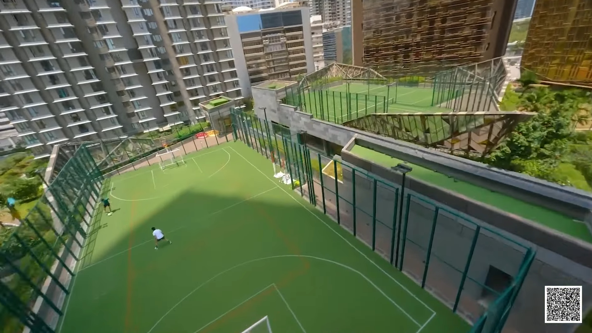 Rooftop football turf and play court between residential towers