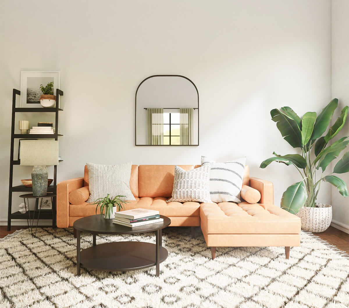 A bright rented living room with a tan sofa, round coffee table and arched mirror