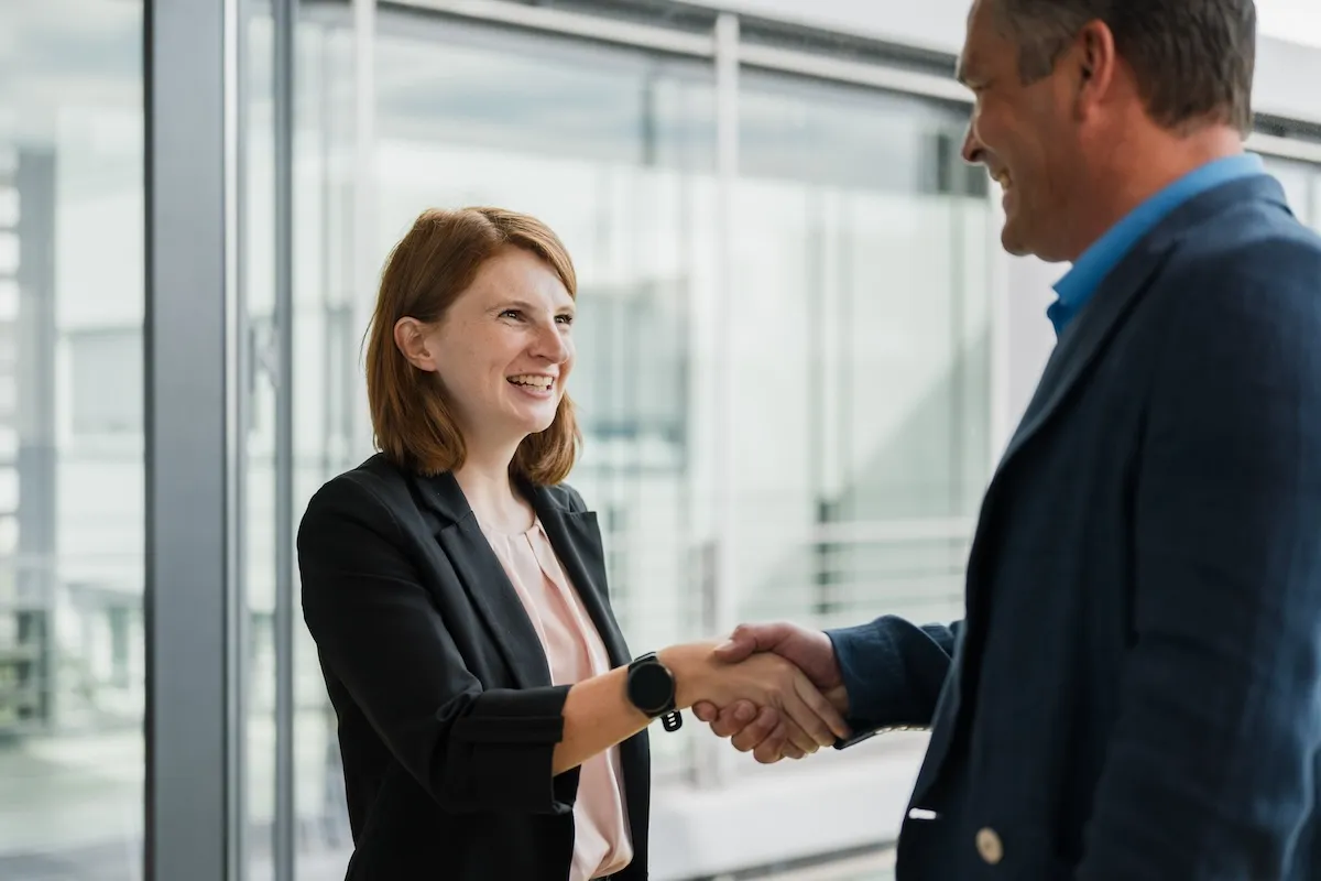 Two persons smiling and giving hand