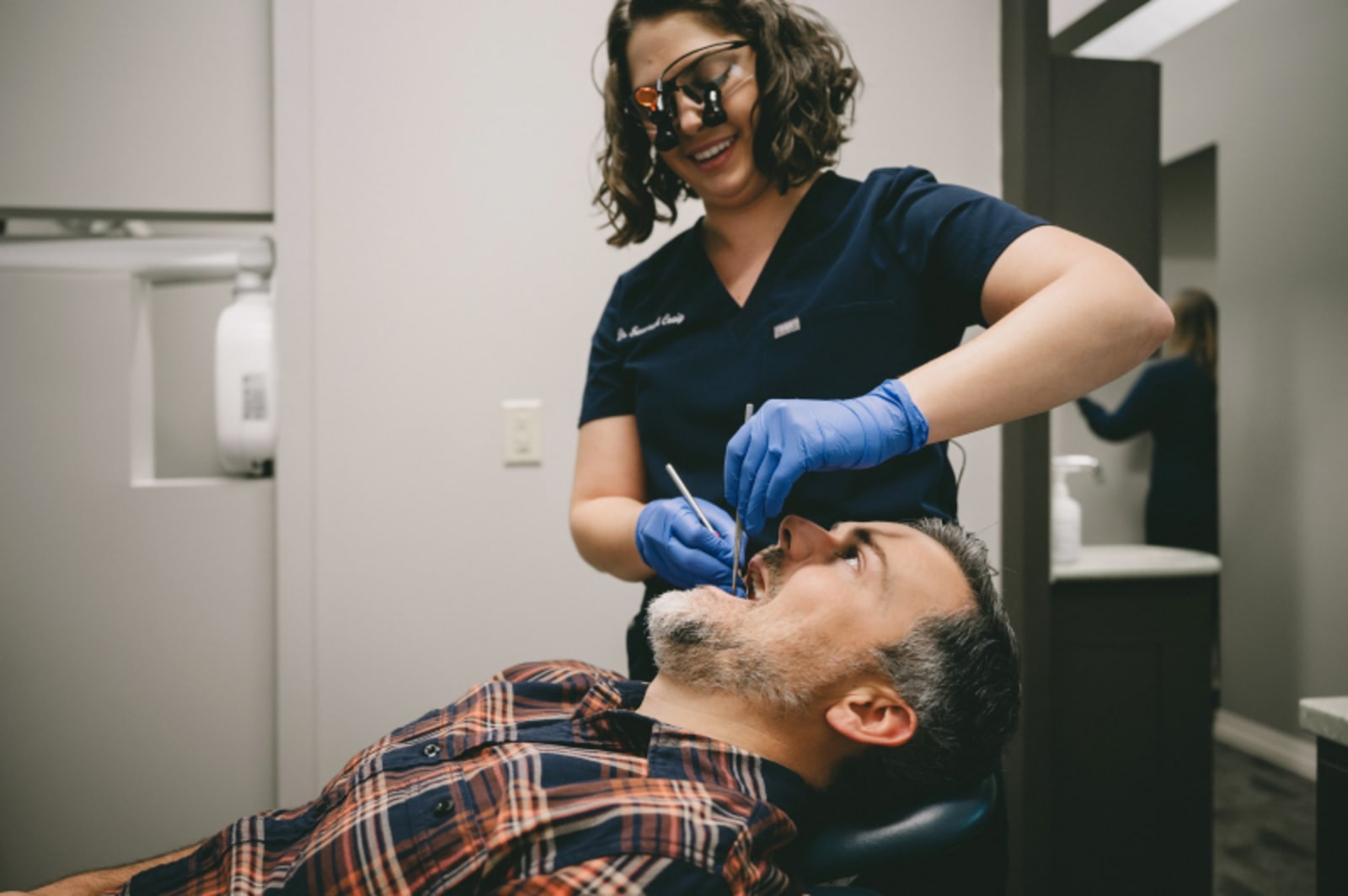 Dentist performing oral examination on patient in treatment chair