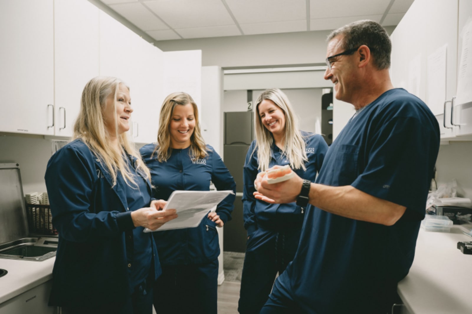 Dentist and team members having friendly conversation during consultation