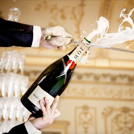 A man sabering a Moët & Chandon champagne bottle — a gesture of panache and French elegance.