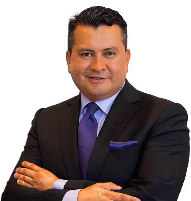 Portrait of a man in a black suit with a purple tie and pocket square, smiling with arms crossed.