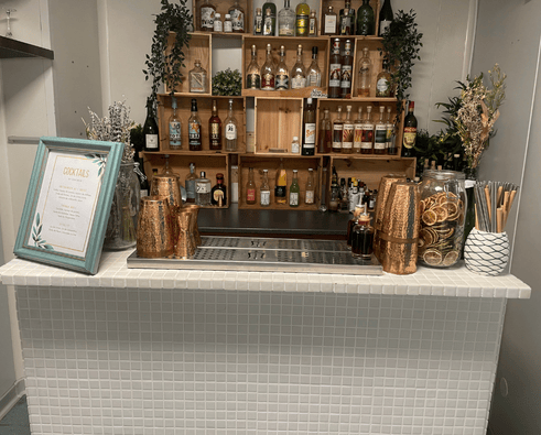 Un groupe souriant assis au bar avec des cocktails.