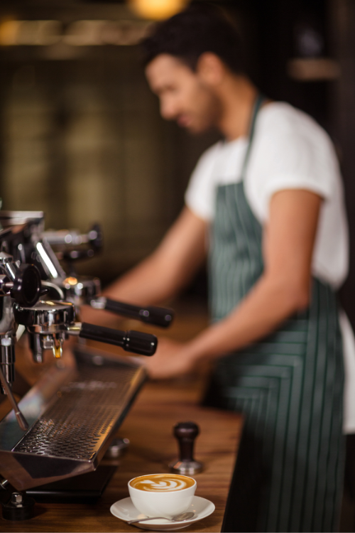 Barman devant un bar extérieur en bois avec un cocktail et des ustensiles en cuivre.