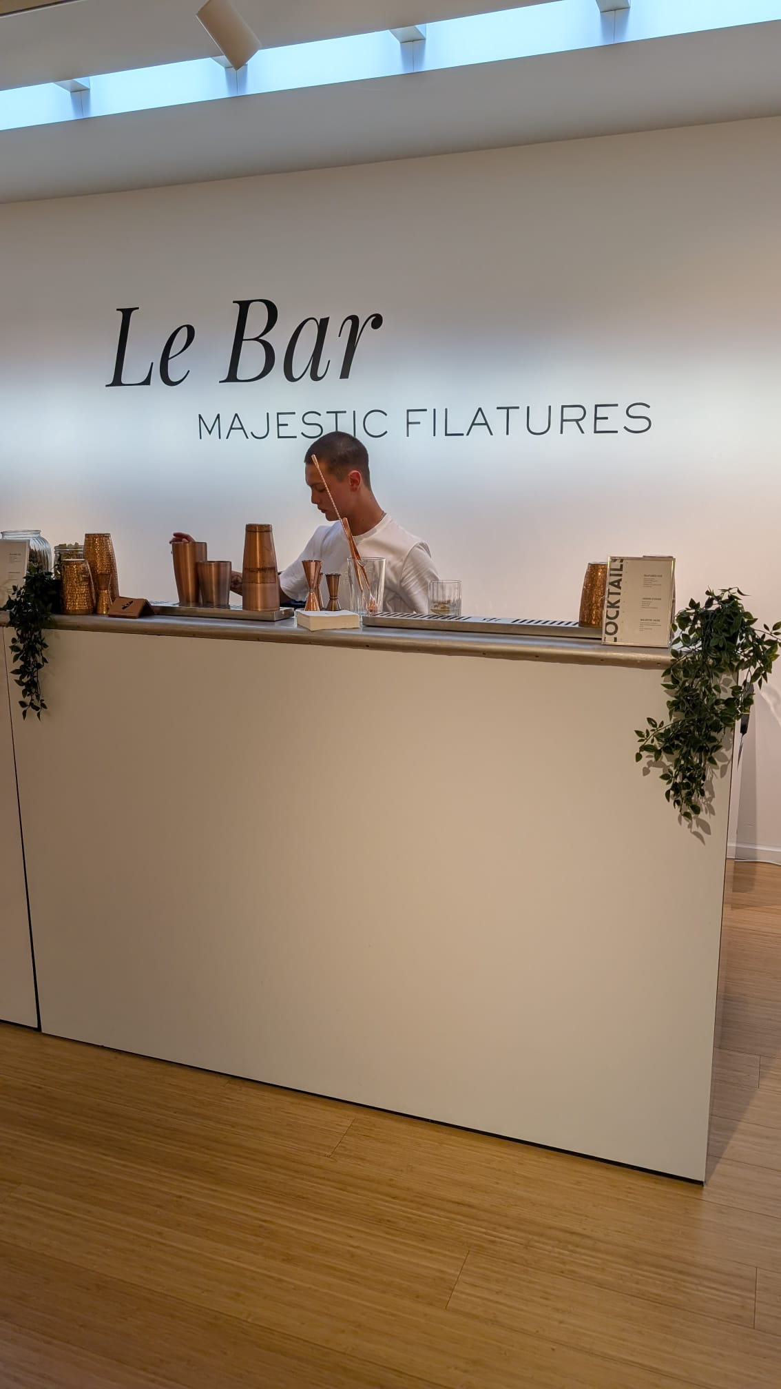 Groupe de collègues autour d'une table, partageant des cocktails colorés dans une ambiance chaleureuse et conviviale, avec des fleurs en décoration et un bar éclairé en arrière-plan.