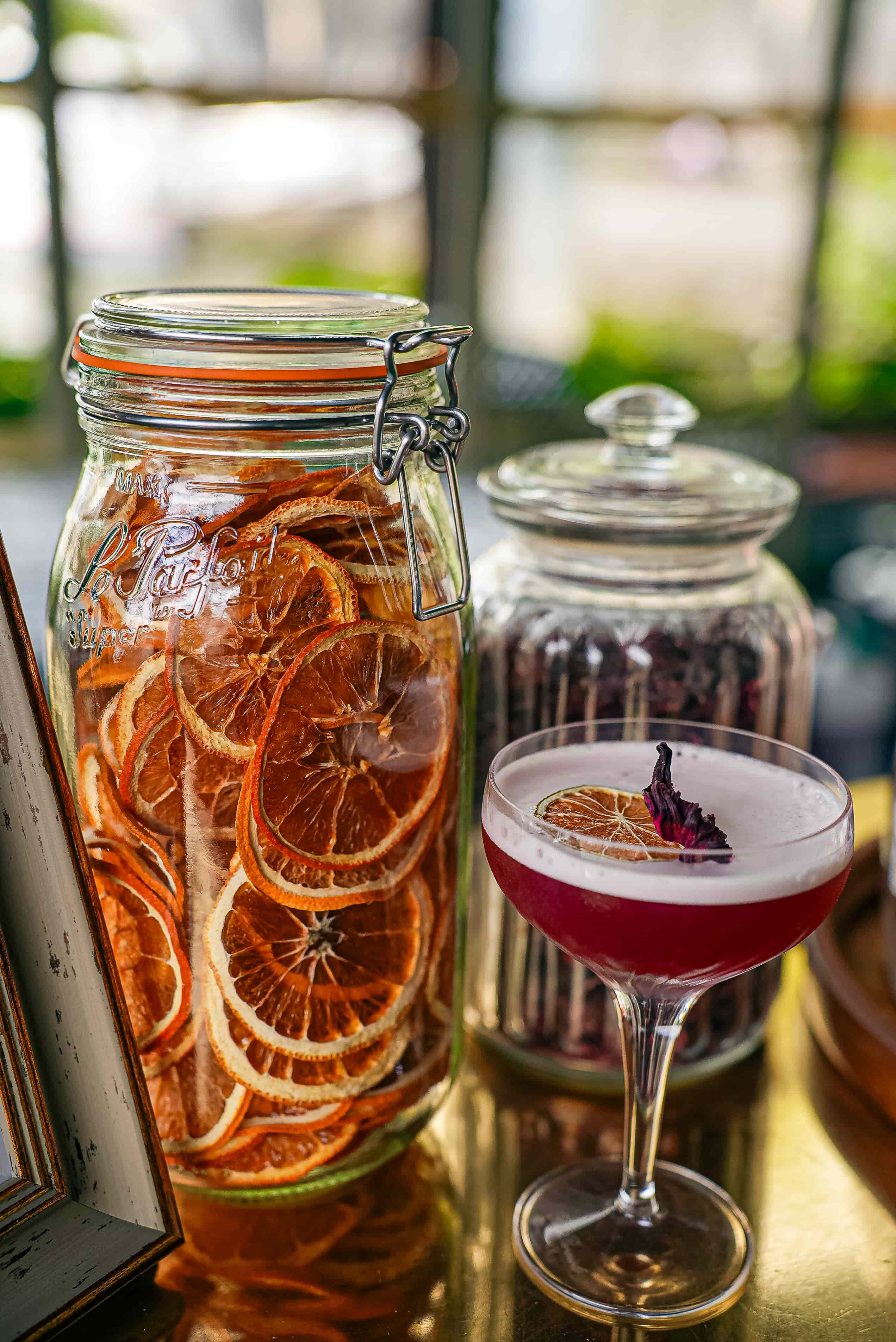 Barman devant un bar extérieur en bois avec un cocktail et des ustensiles en cuivre.