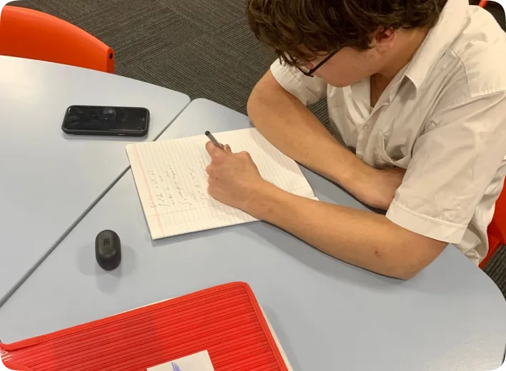 A man sitting at a table writing on a piece of paper