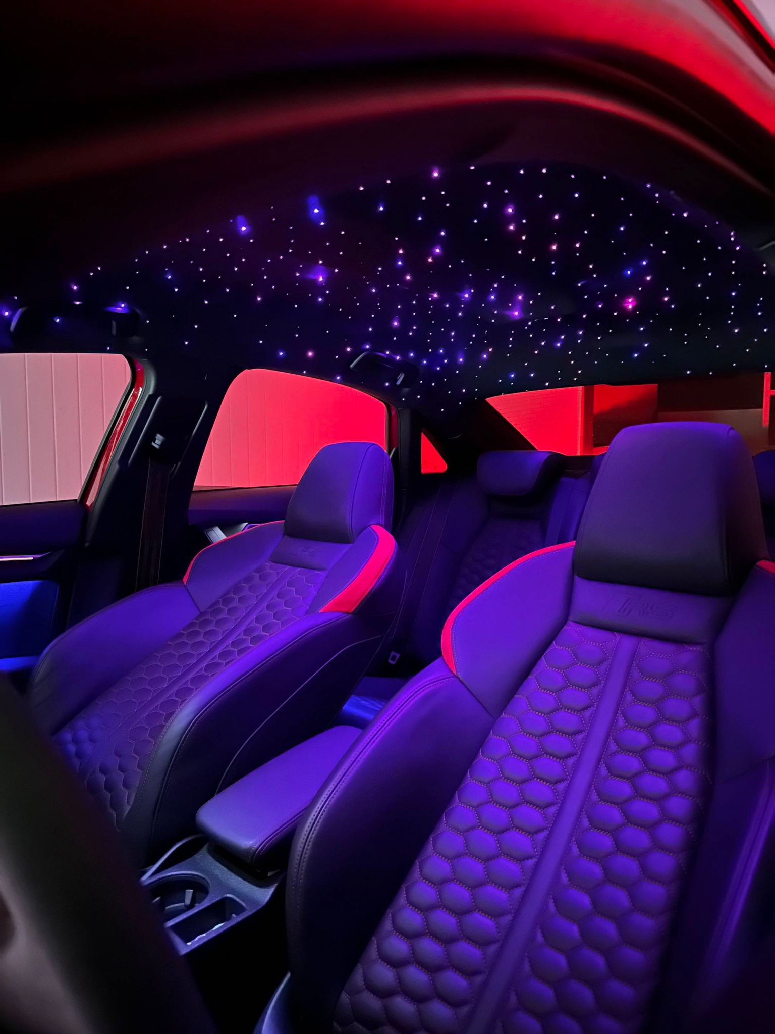 Car interior with illuminated star points across the headliner and purple ambient lighting.