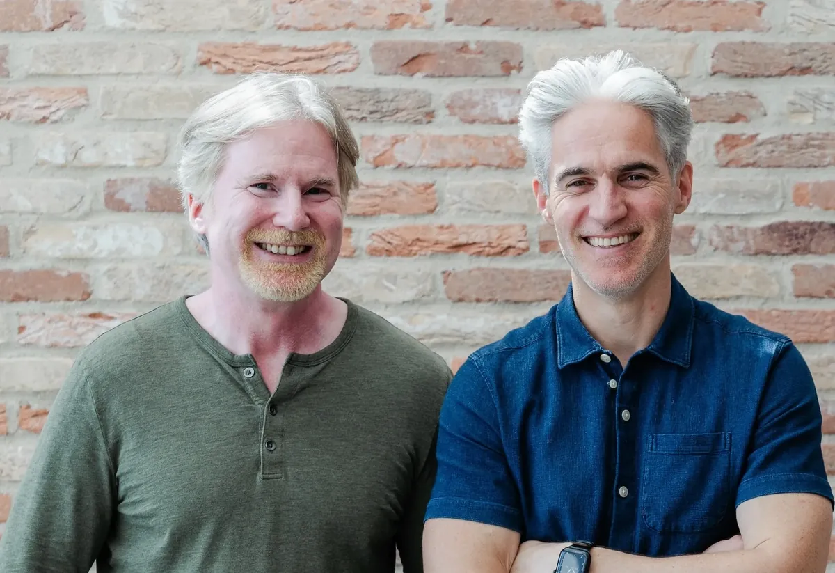 Founders Lars and Glenn smiling in front of a brick wall