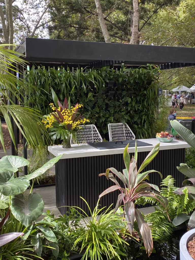 Modern outdoor kitchen with lush tropical plants and yellow flowers