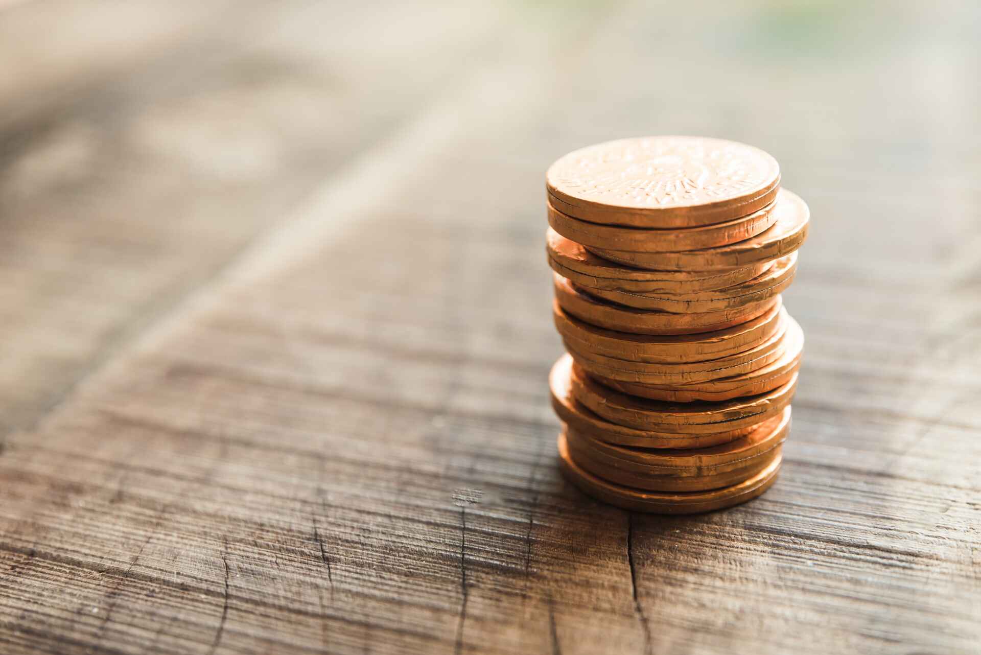 Stack of copper or bronze coins on rustic wooden surface