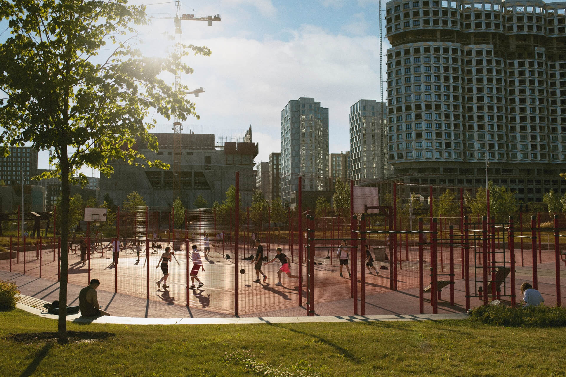 People playing ball in urban fenced court surrounded by high-rise buildings
