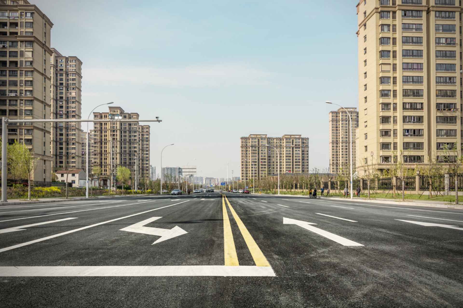 Wide urban street with high-rise apartments and directional arrow markings