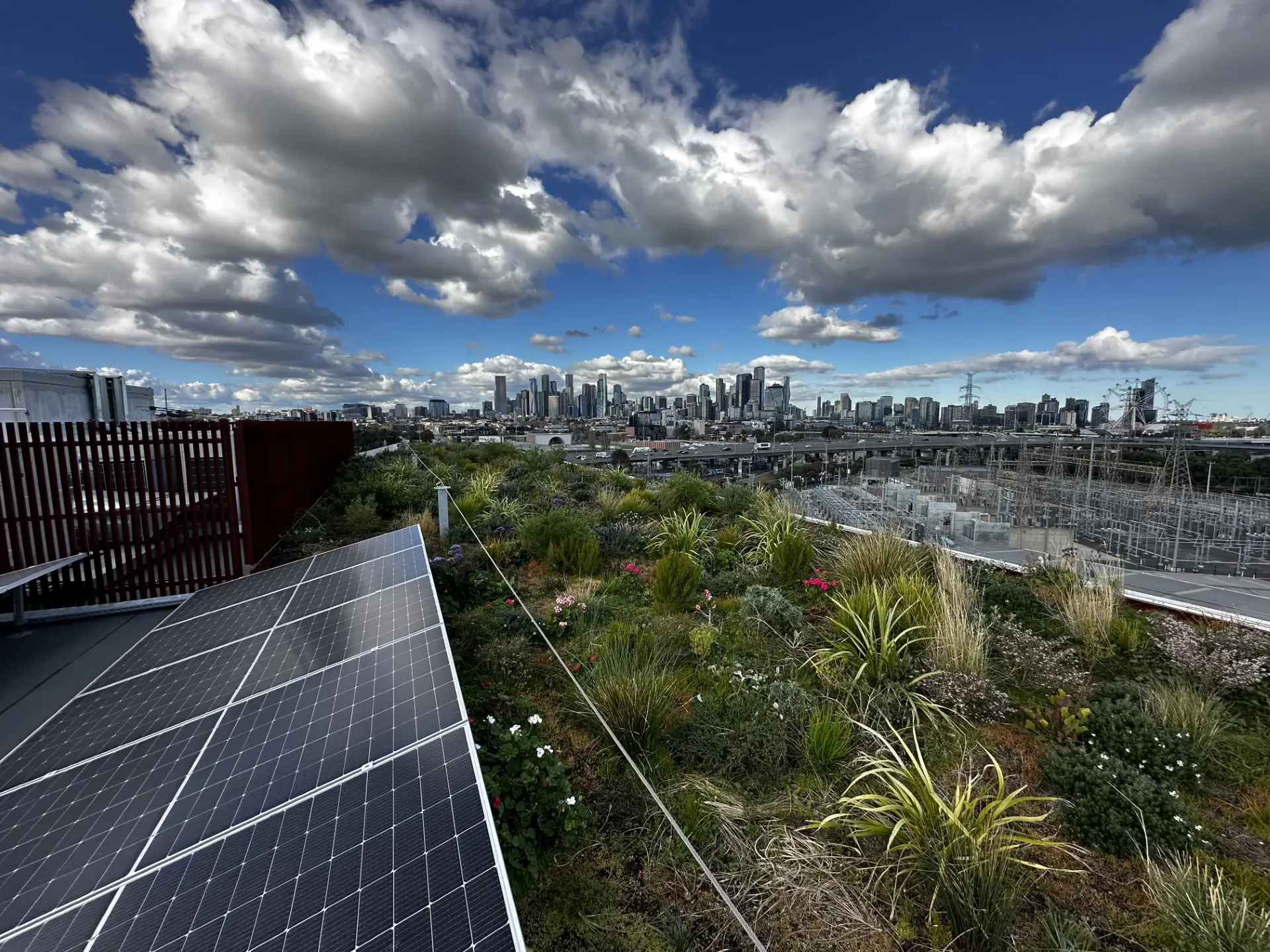 Urban rooftop with solar panels and green garden overlooking city skyline