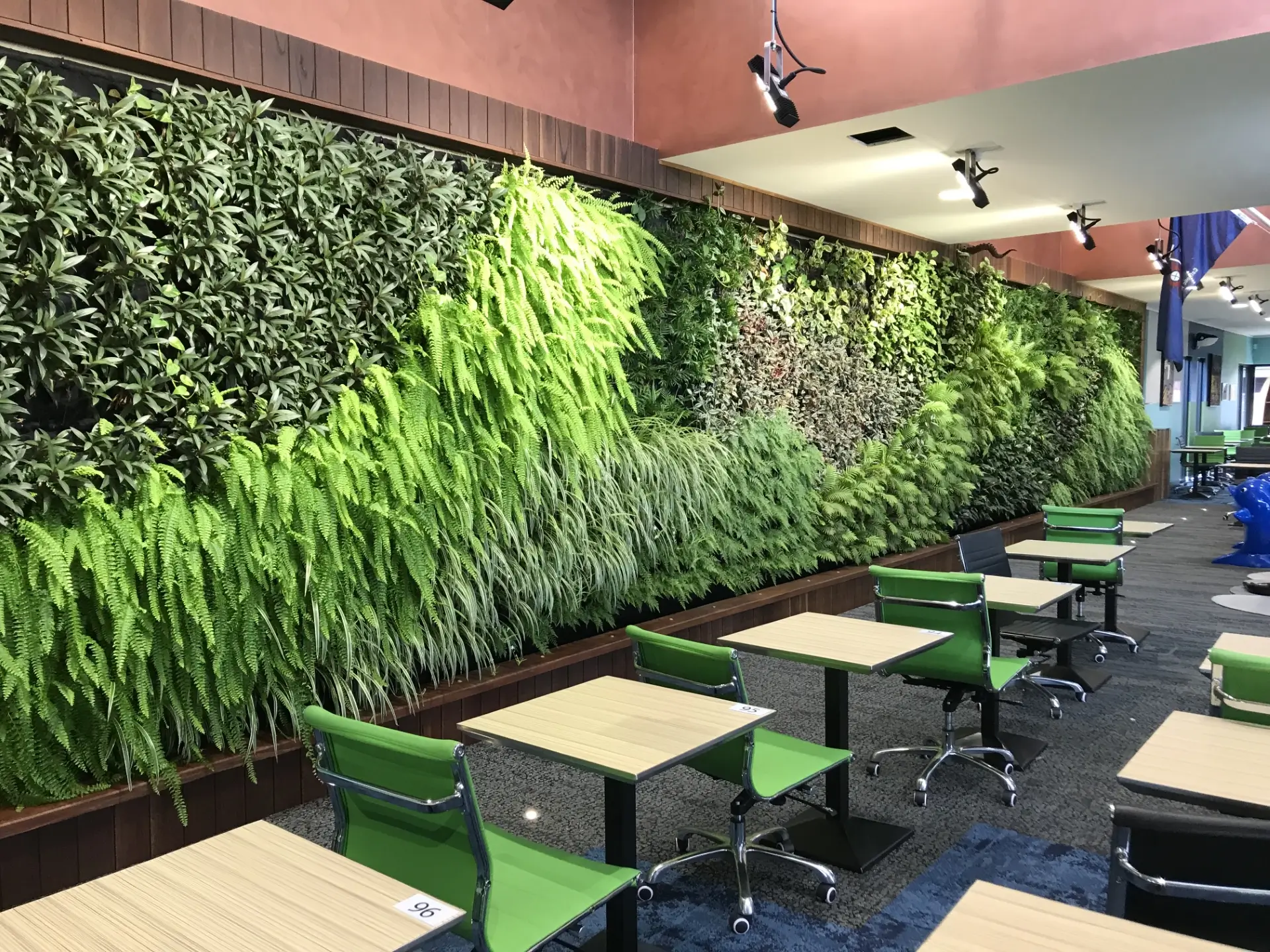 Green living wall with study tables and green chairs in modern workspace