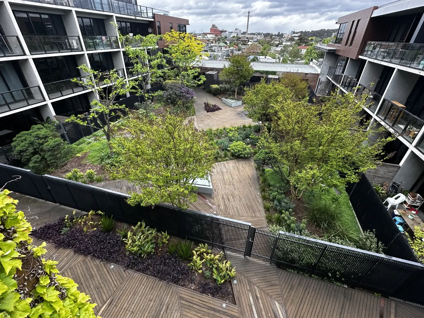 Modern apartment complex with lush green courtyard and wooden walkways