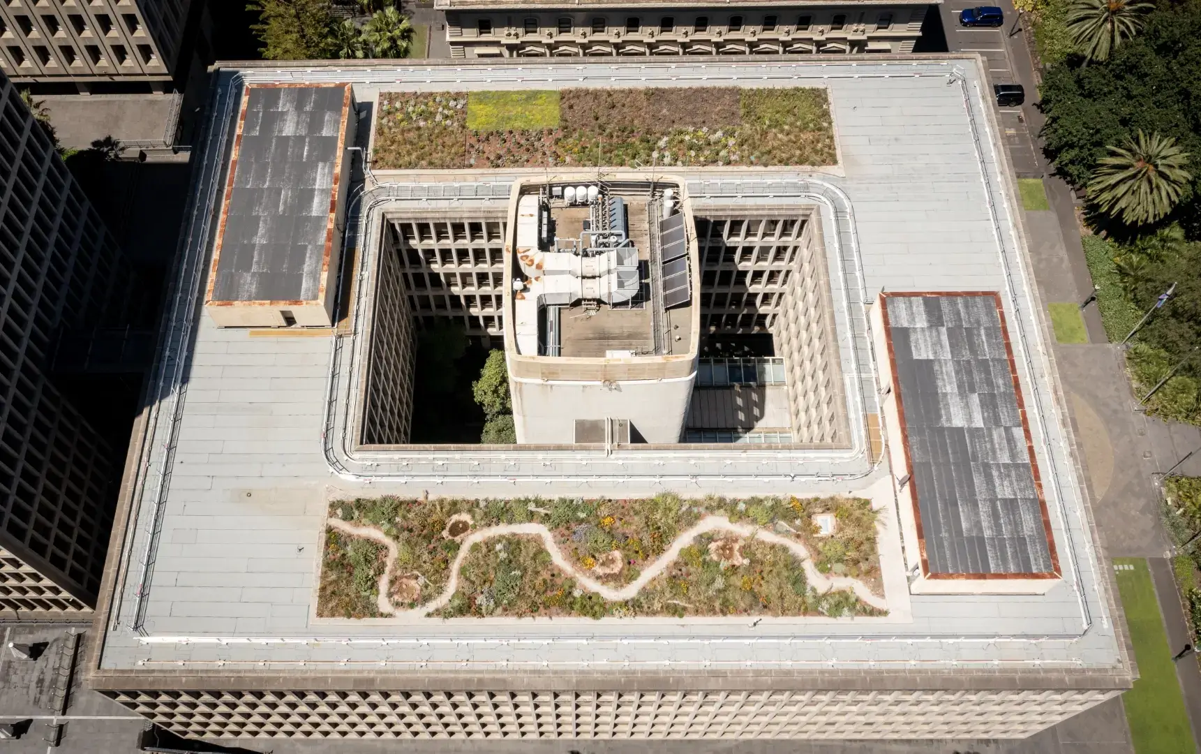 Aerial view of modern building with green rooftop gardens and winding path