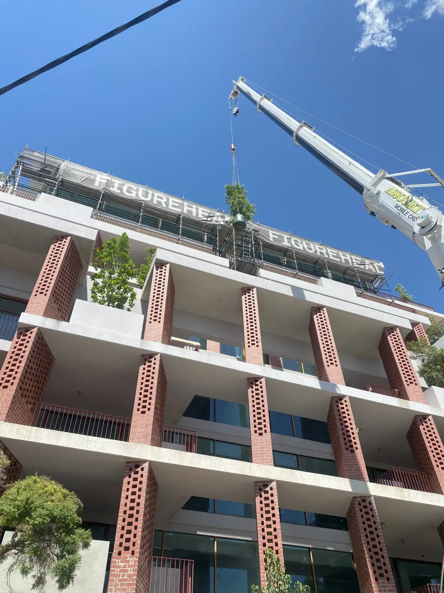 A crane lifting a plant onto an apartment roof