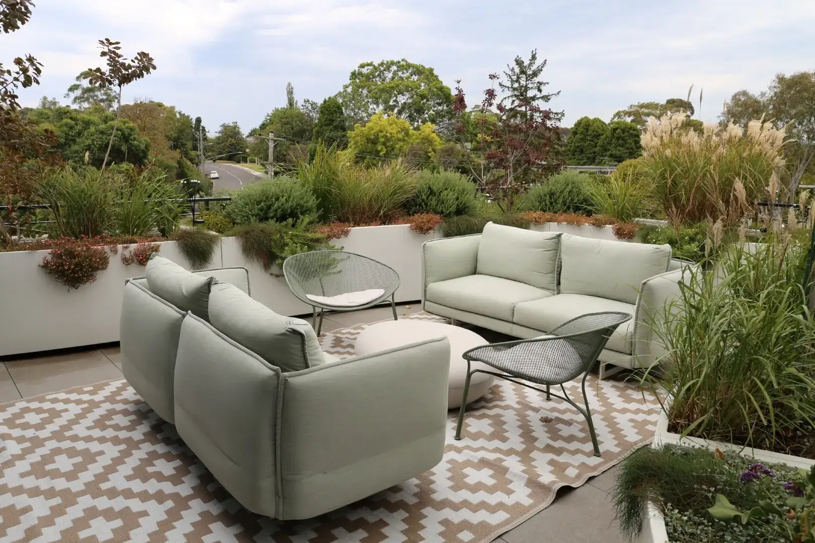 Rooftop terrace with sage green furniture and ornamental grasses