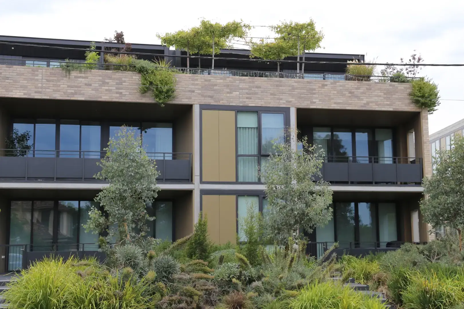 Modern apartment building with green rooftop and landscaped garden surroundings