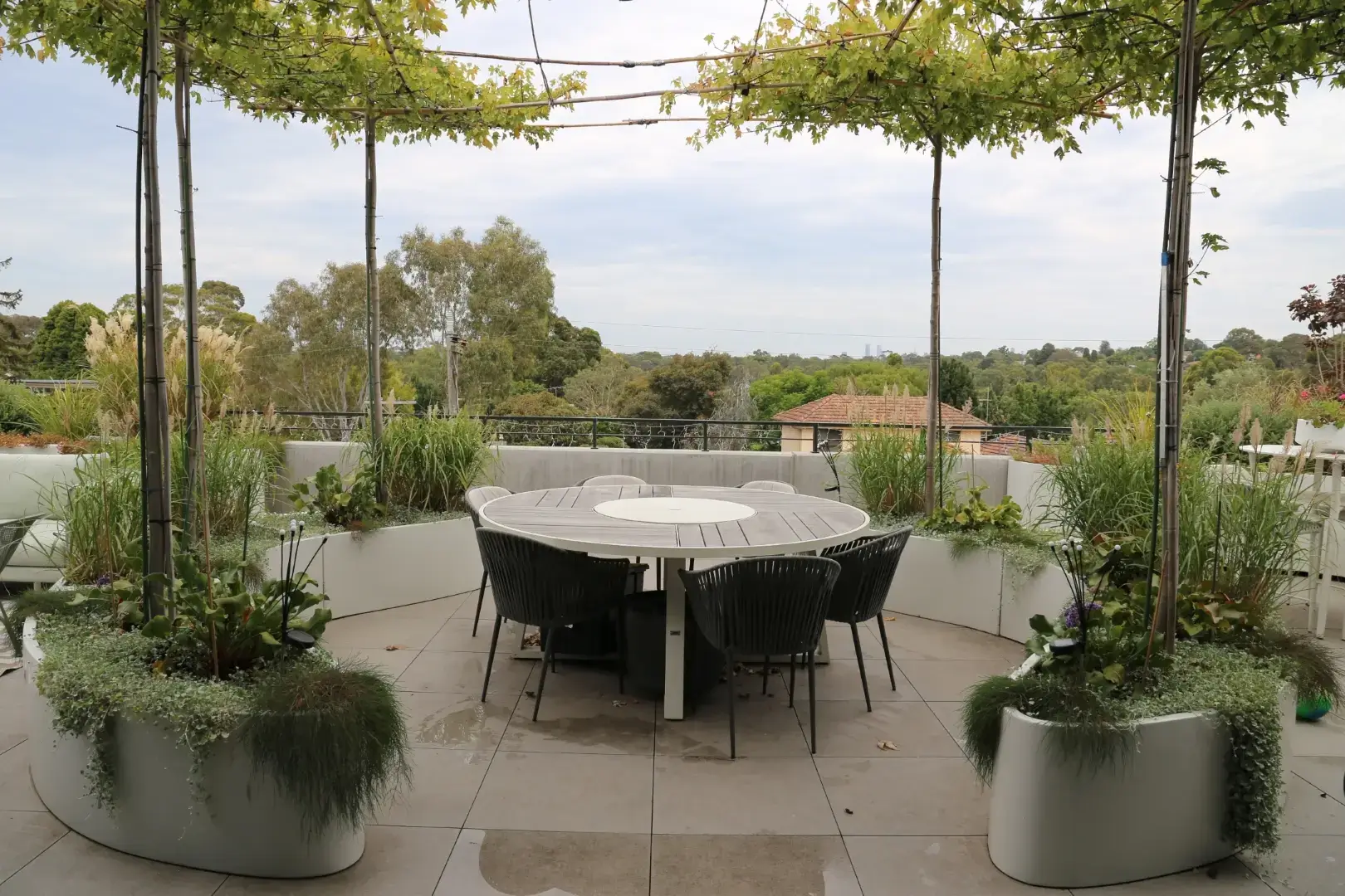Rooftop garden with round dining table, plants, and scenic landscape view